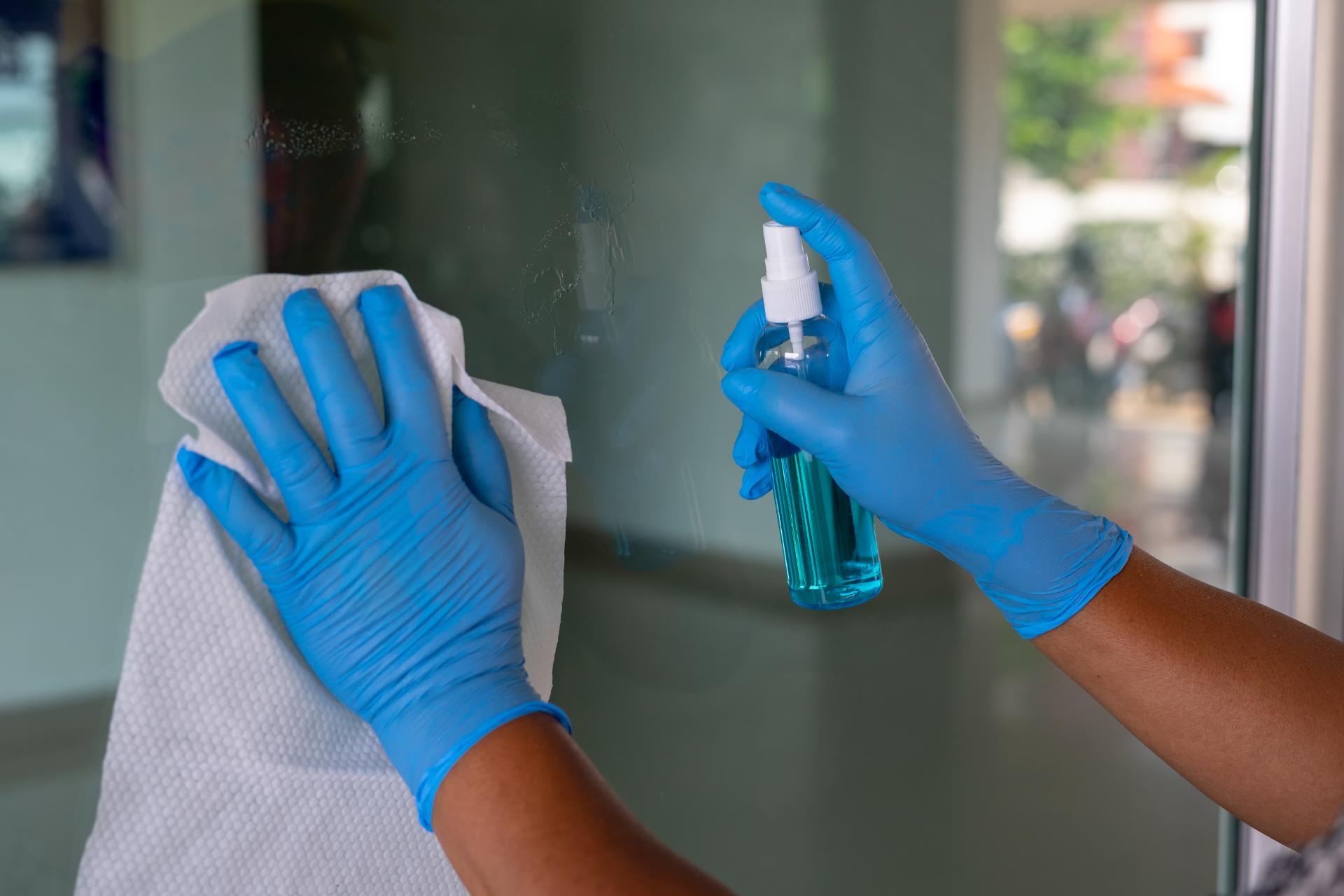 Persona limpiando un cristal con guantes azules